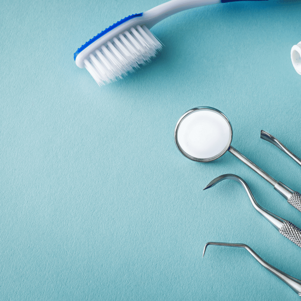 A toothbrush and three dental tools, including a mouth mirror and probes, are arranged on a light blue background.